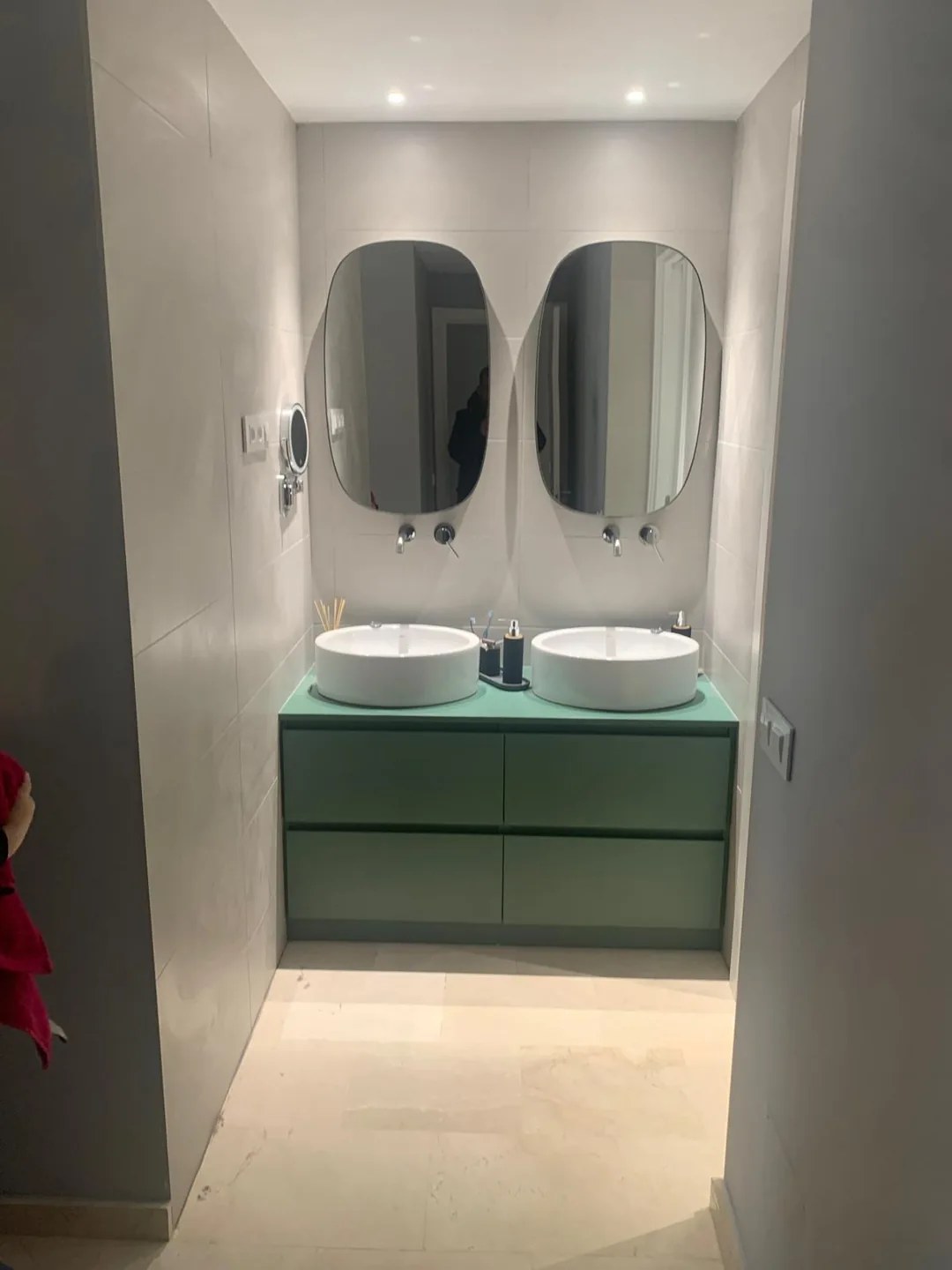 Baño de microcemento con doble lavabo y mueble verde suspendido