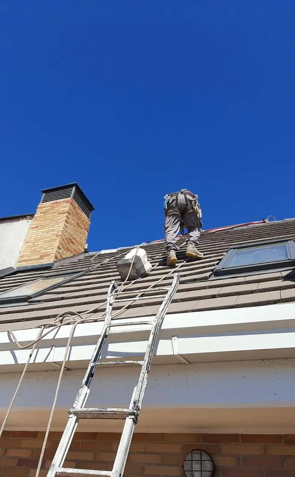 Operario de Welldone Reformas trabajando sobre una cubierta inclinada con cielo azul