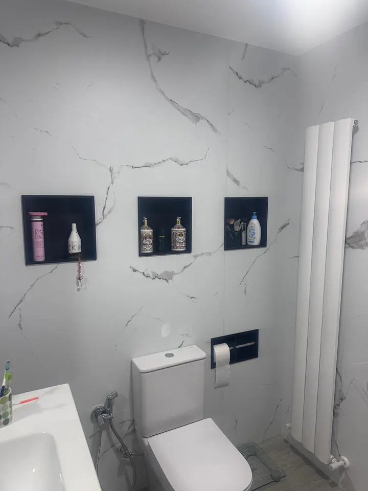 Baño en mármol con hornacinas empotradas y radiador vertical