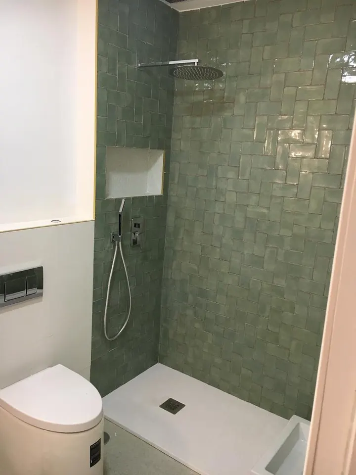 Ducha reformada con azulejo verde artesanal y columna empotrada